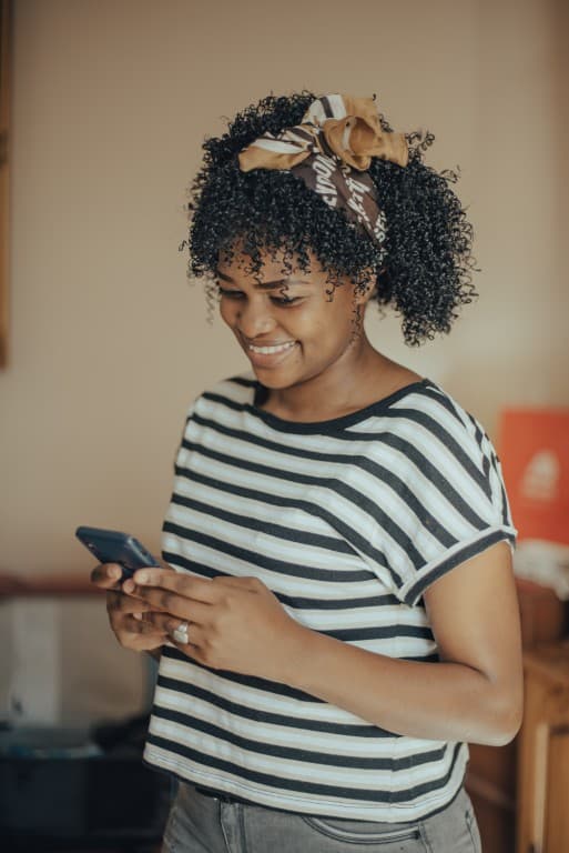 Woman smiling while looking at her smartphone indoors