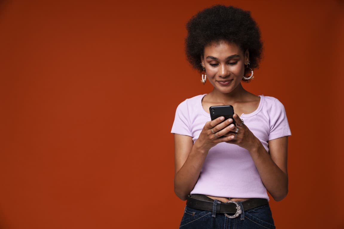 Woman using her mobile phone against an orange background