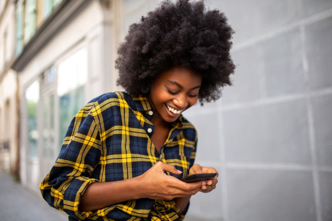 Young woman walking on the street using her phone