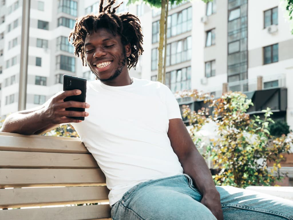 Man smiling at his phone in a city setting