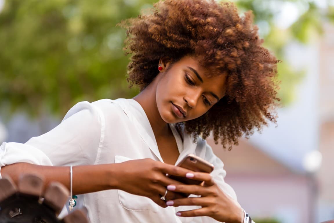 Woman using her mobile phone on a bench outside