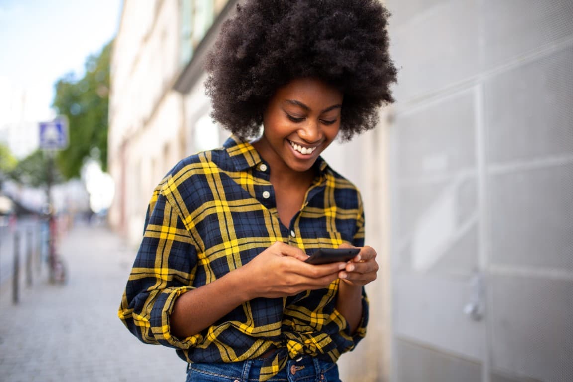 Woman topping up airtime while walking down the street